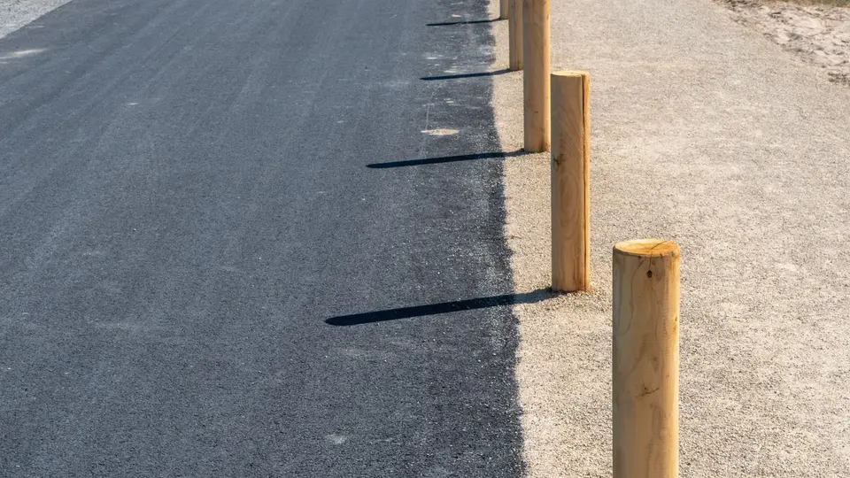 Edge of a new asphalt surface meeting a compacted aggregate shoulder